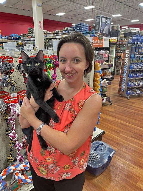 Black cat held by a woman in an orange shirt