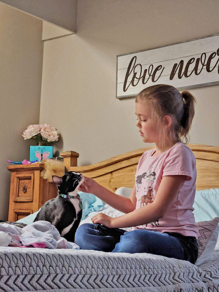 Girl and her cat sitting on a bed